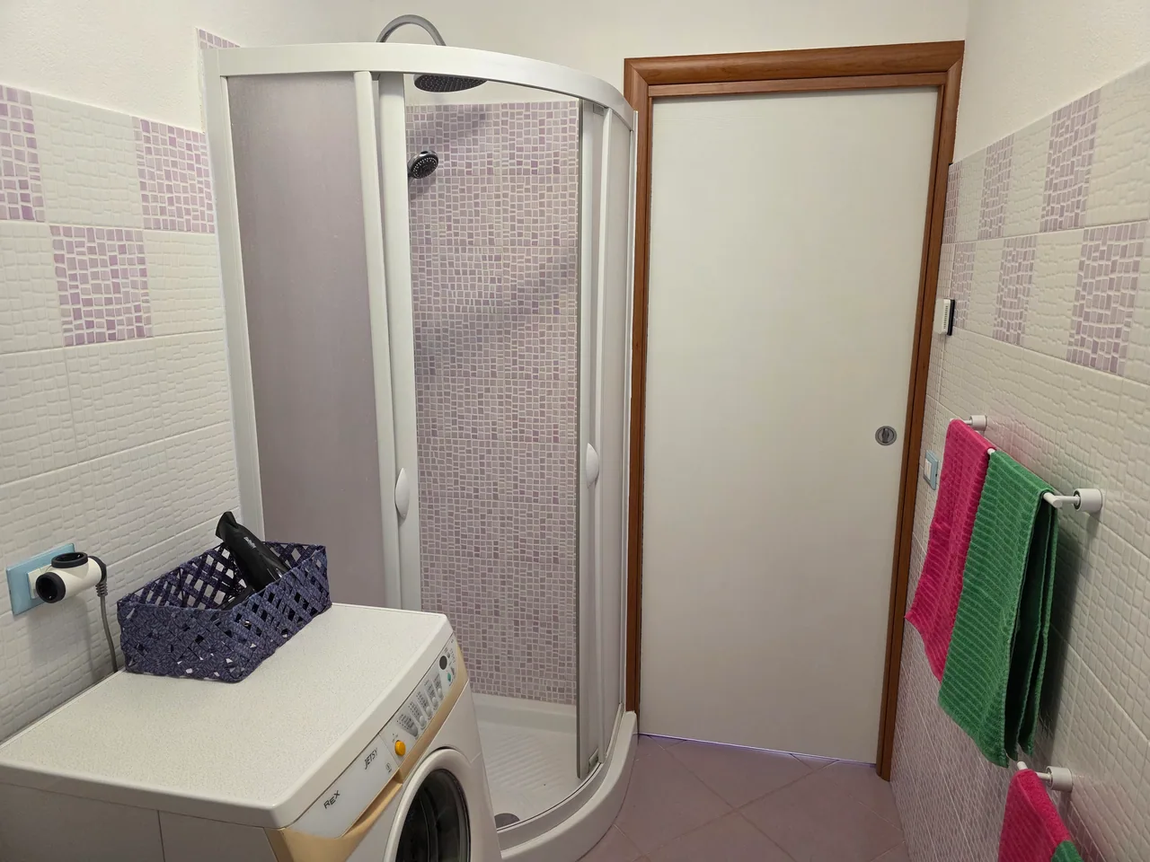Il box doccia e la zona lavatrice del bagno.